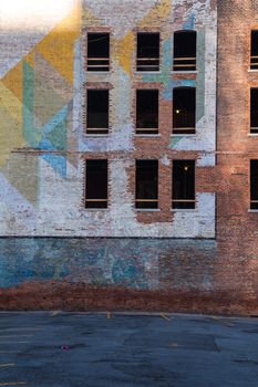Old abandoned building in the downtown of Detroit. Facade made of bricks, partly with a colorful painting. Broken windows.