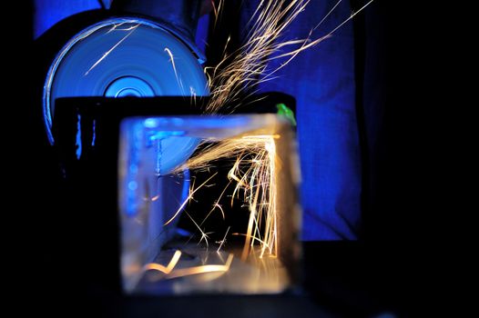Worker cutting metal with grinder. Sparks while grinding iron