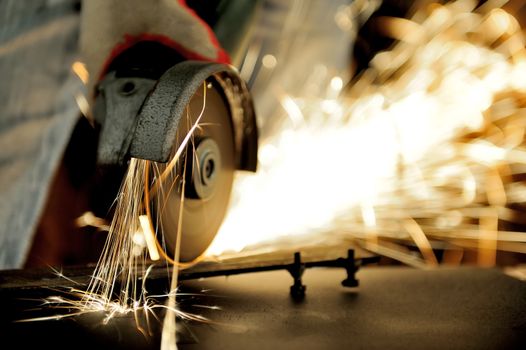 Worker cutting metal with grinder. Sparks while grinding iron