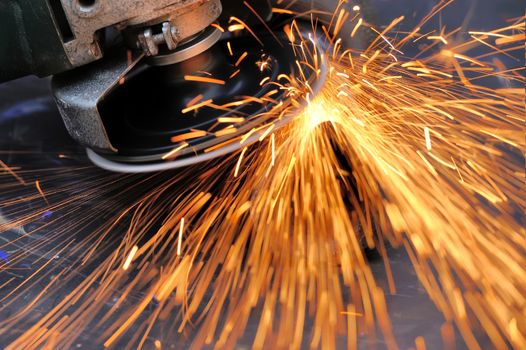 Worker cutting metal with grinder. Sparks while grinding iron