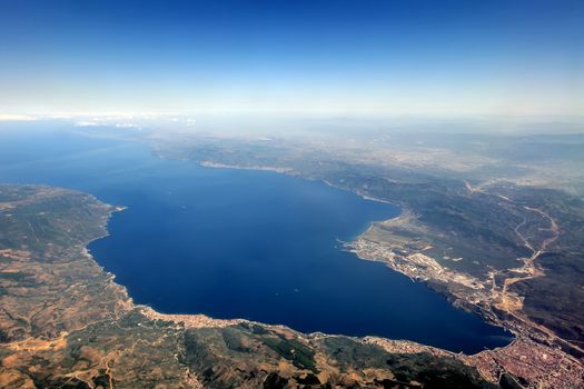 View from airplane window with sea, town, mountain