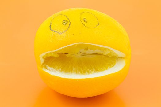 Funny orange with eyes, nose and mouth on an orange background.