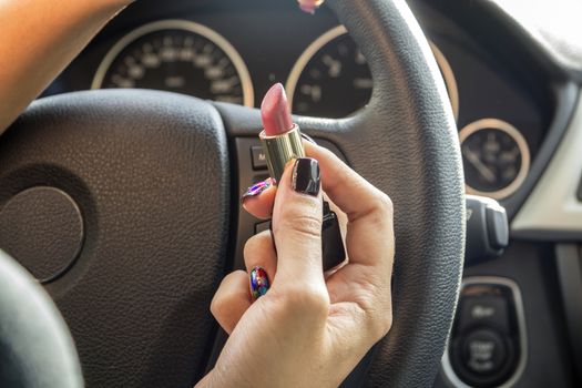 Arm girls with trendy manicure keeps lipstick while driving in the car