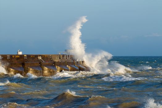 Waves breaking over the east arm of Brighton Marina, on the South Coast of England, during windy weather and high seas in the English Channel.