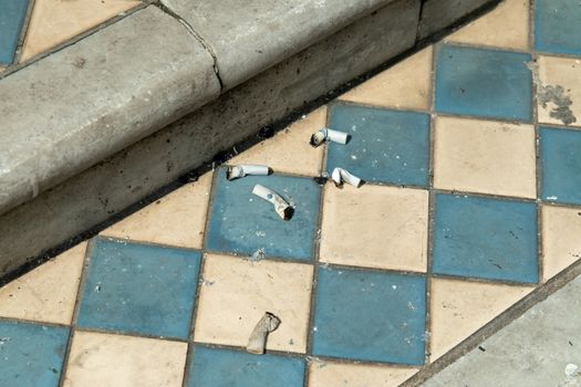 Discarded and extinguished cigarettes on tiled step of old house.