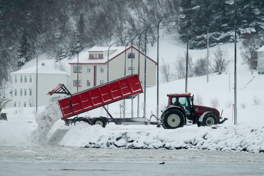 Tipper truck dumping cleared snow into Eyjafjörður fjord in Akureyri, Iceland.