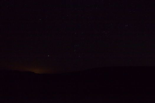 Stars over Scotland during March. Orion, Taurus, The Pleiades and Sirius visible, with horizon and light from distant town.