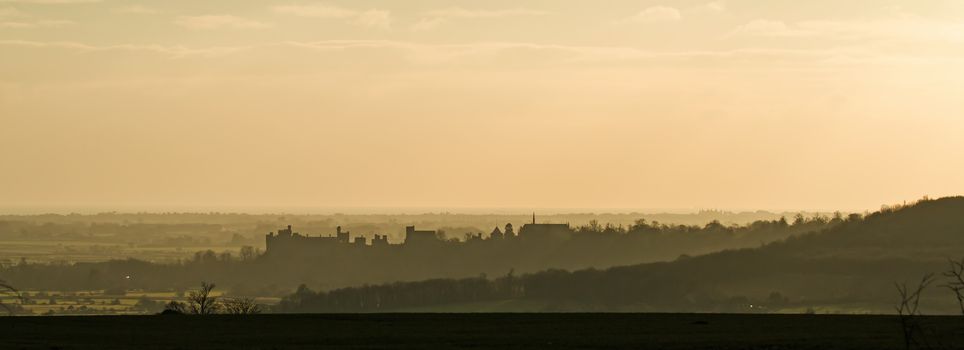 West Sussex country town of Arundel at sunset, with Arundel Castle and Arundel Cathedral silhouetted and the English Channel beyond.