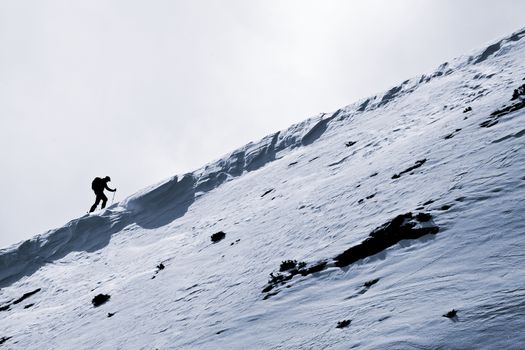 Small figure of skier, climbing a mountain