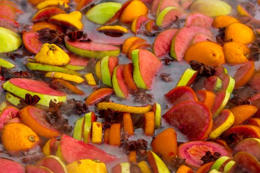 Cooking fruits and spices mulled wine in a large bowl