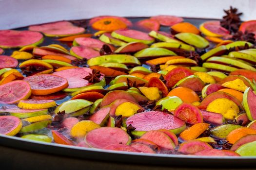 Cooking fruits and spices mulled wine in a large bowl