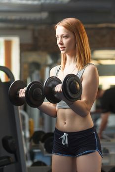 Concept: sport, healthy lifestyle. Young strong girl do exercises with dumbbells