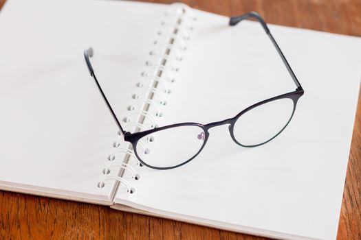 Eyeglasses on opened spiral notebook , stock photo