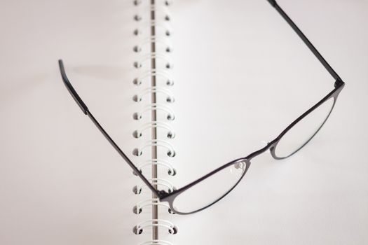 Eyeglasses on opened spiral notebook , stock photo