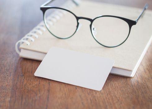 Blank business cards and eyeglasses on wooden table, stock photo