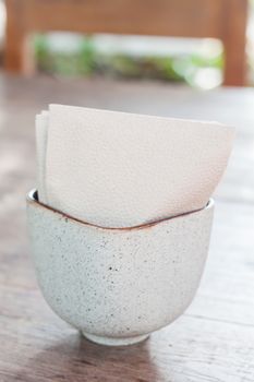 Tissue paper in ceramic cup on wooden table, stock photo