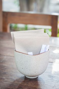Tissue paper in ceramic cup on wooden table, stock photo