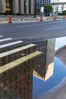 Morning after a rainy night. Road with a crosswalk and a puddle, reflecting the skyscrapers in Detroit downtown, USA