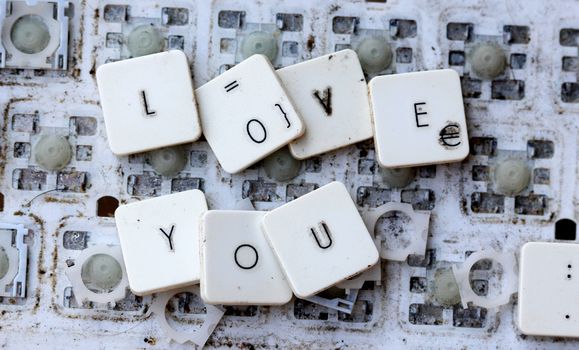 A close view of some keys on a dirty, yellowed keyboard.text i love you