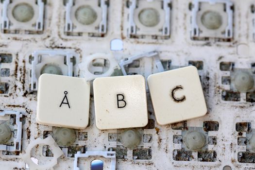 A close view of some keys on a dirty, yellowed keyboard.letters a,b and c