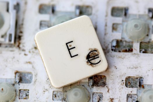 A close view of some keys on a dirty, yellowed keyboard.letter e