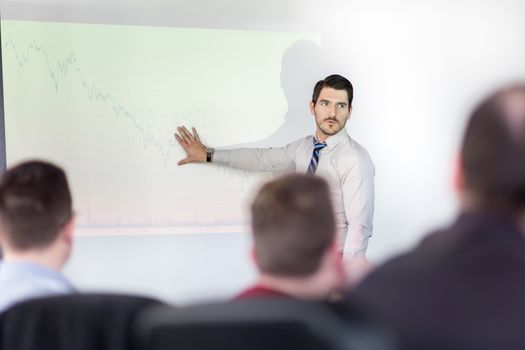 Business man making a presentation at office. Business executive delivering a presentation to his colleagues during meeting or in-house business training, explaining business plans to his employees.
