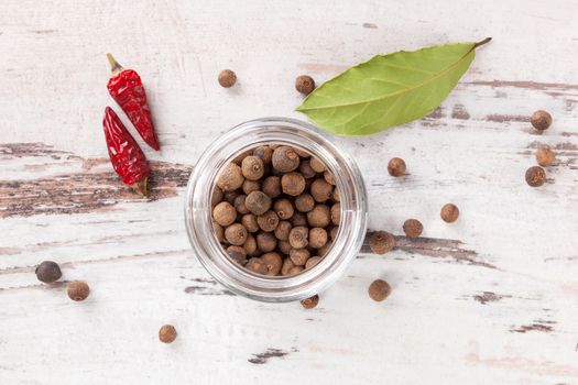 Traditional spice and condiment wooden background. Bay leaves, chillies and black pepper on wooden table, top view.
