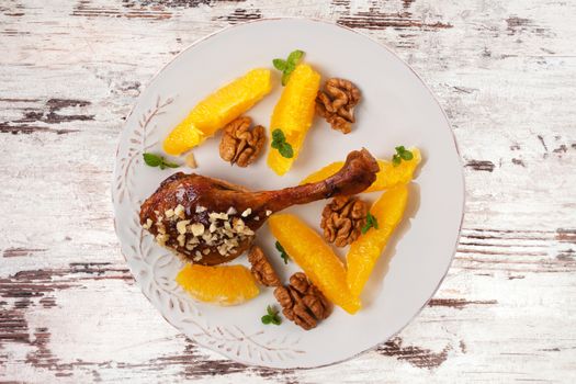 Luxurious roast duck with fruit and nuts on plate on wooden background, top view. Culinary roast duck eating. 