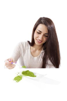 Detox. Beautiful girl with green ground powder on spoon isolated on white. Spirulina, chlorella and wheatgrass. Healthy lifestyle, detox.