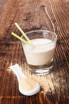 Maca powder on spoon and maca powder shake on brown wooden aged table. Healthy living, alternative medicine, rustic style.