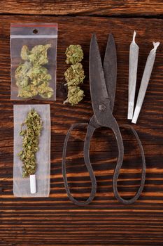 Marijuana background. Cannabis joint, bud in plastic bag and hemp leaves on wooden table. Addictive drug or alternative medicine. 