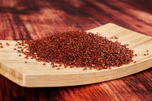 Red quinoa seeds on brown wooden table. Healthy eating.