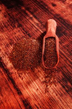 Red quinoa seeds on brown wooden table. Healthy eating.