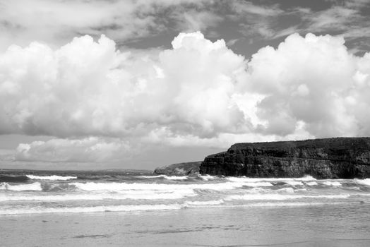 lone surfer on waves at the cliffs and beach in ballybunion on the wild atlantic way