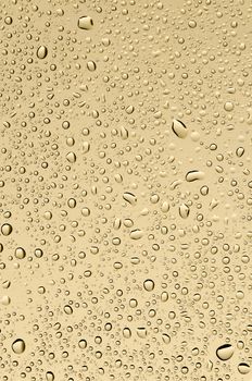 Water drops on a background of sand-yellow glass. Texture background.