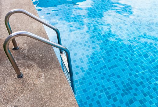 Staircase into the swimming pool with blue tiled. View from eye.