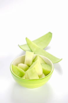 shopped green melon in bowl on white background