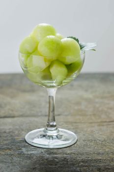 Fresh green cantaloupe melon in glass on wooden background