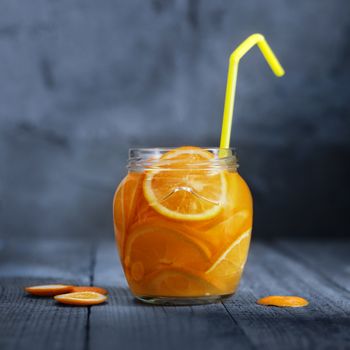 Lemonade with orange in glass jar on old wooden boards. Rustic style, bokeh