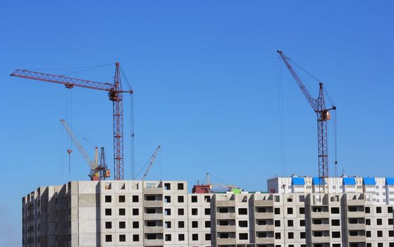 Industrial landscape with silhouettes of cranes on the sky background