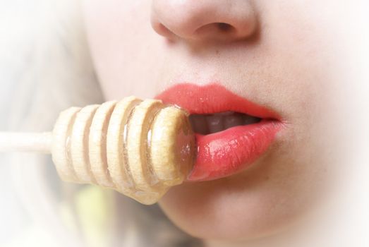 Closeup view on an attractive womans lips while eating honey from a stick.