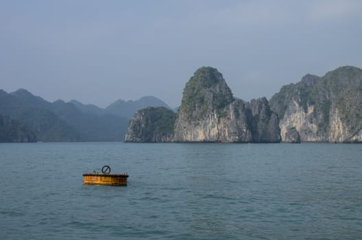 Beautiful limestone mountain scenery with yellow buoy at Ha Long Bay, North Vietnam. Cloudy winter weather