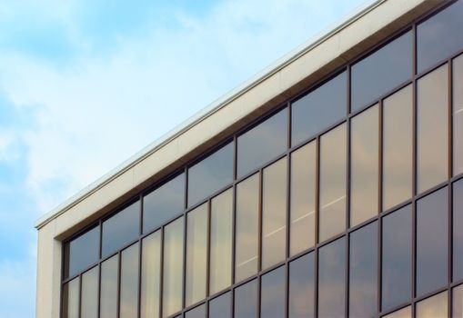 modern building on blue sky, beige and dark windows corner perspective