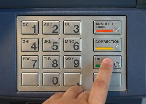 finger pressing buttons on cash machine to enter nip code on the keypad