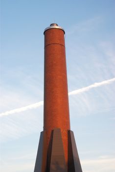 big red bricks cylindrical chimney on blue sky, no smoke