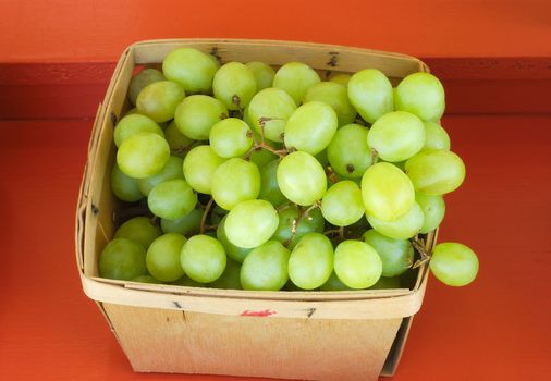 green grapes at the market in wooden basket on red background