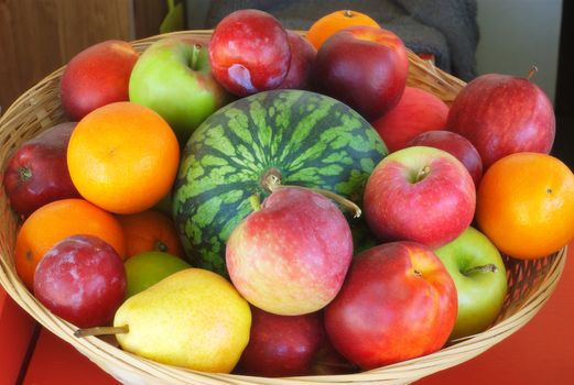 basket of fruits with watermelon, different kinds of apples, oranges, pears, plums and nectarines