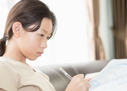 Asian girl doing her homework, writing on a lesson book