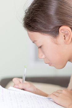 Asian girl doing her homework, writing on a lesson book