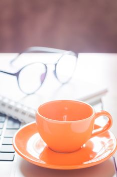 Laptop with coffee cup and notepad on desk, stock photo